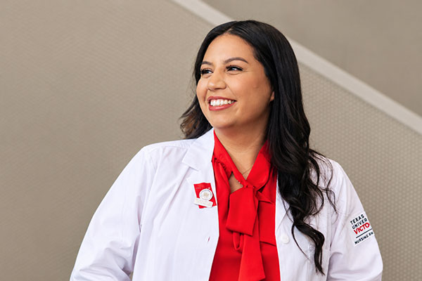 Nursing student with white nursing jacket on looking to the left.