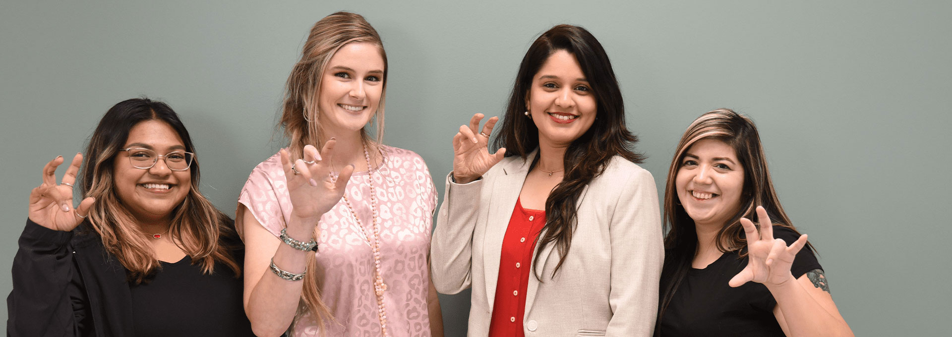 Four individuals pose for a photo while doing the Jaguar handsign.