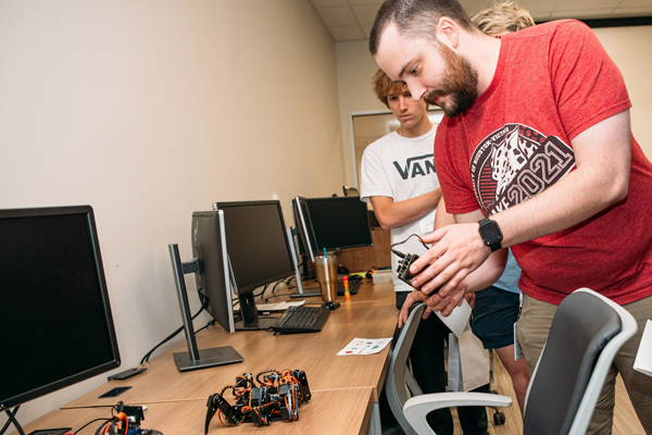 <img src="/media/tamuv/college-of-natural-and-applied-science/images/students-robotics-lab-computer-science.jpg" alt="Two students collaborating on a robotics project in a computer lab, with one examining a small robot on a desk surrounded by computer monitors" style="width: 600px; height: 400px;     " />