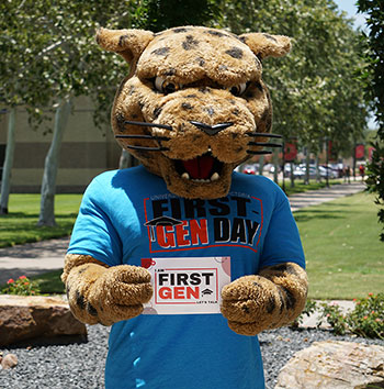 Jax, the UHV mascot, wears a First Gen Day t-shirt and holds a door placard used by First Gen staff members