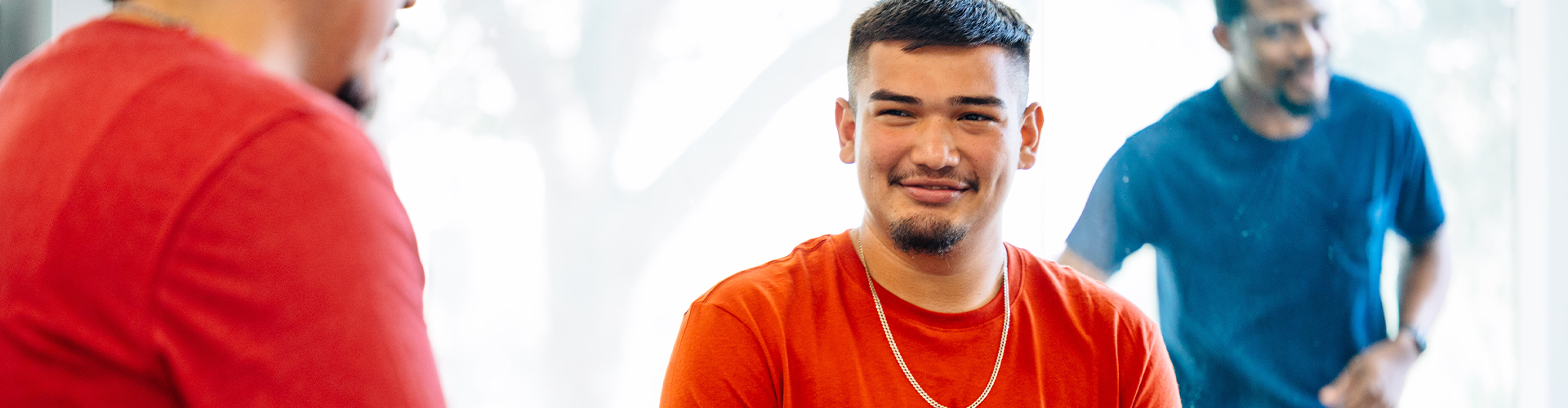 Student with an orange shirt smiling at someone off camera.