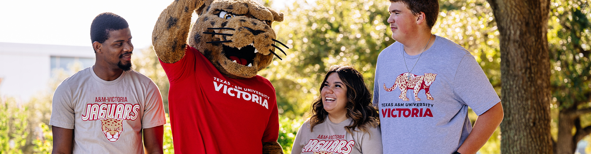 Three students and Jax the mascot smiling.