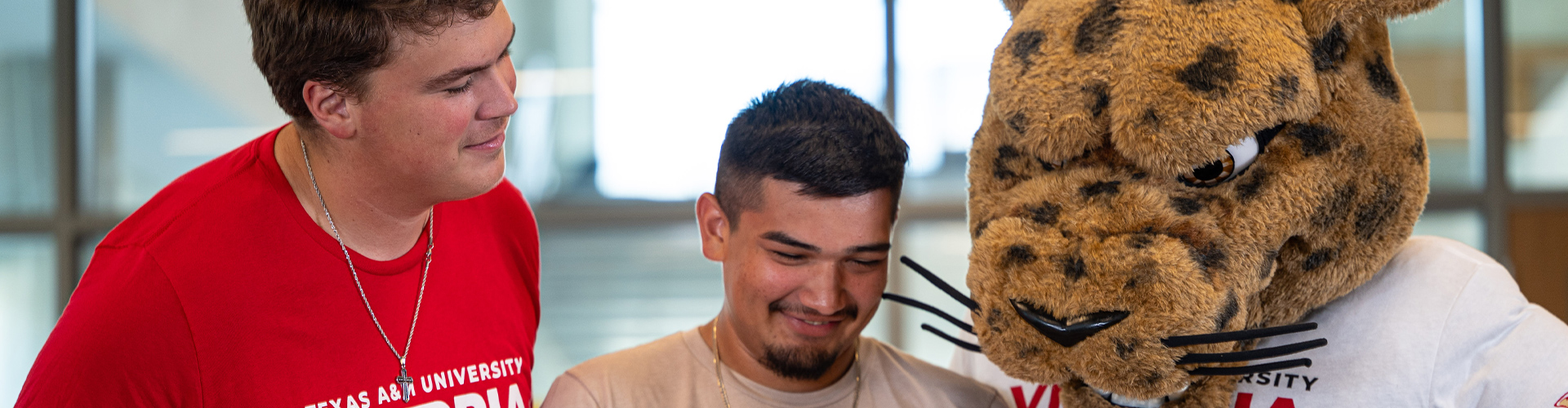 Two students and Jax the mascot looking down.