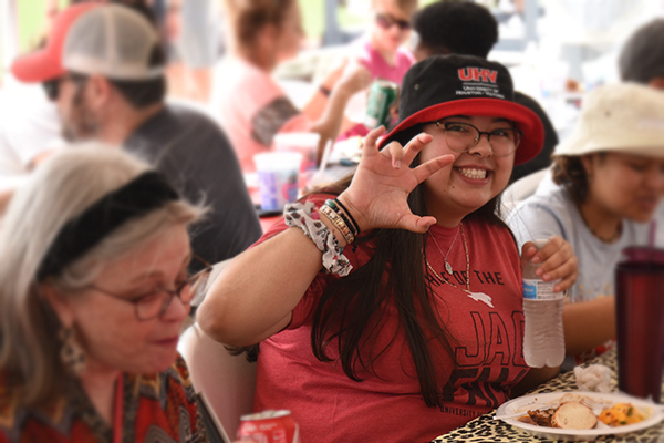 A female student wearing UHV apparel, doing the UHV Hand Sign