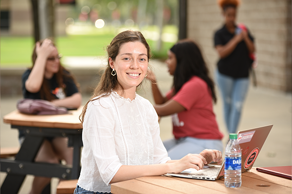female student outside with laptop