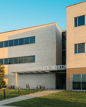 UNIVERSITY NORTH with outdoor seating on a grassy lawn under a clear blue sky