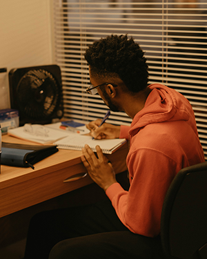 Student sitting at a desk and writing in a notebook.
