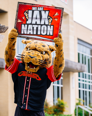 jaX holding "We Are Jax Nation" sign in front of University West building