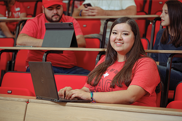 A female student, with a laptop, sitting in an auditorium.