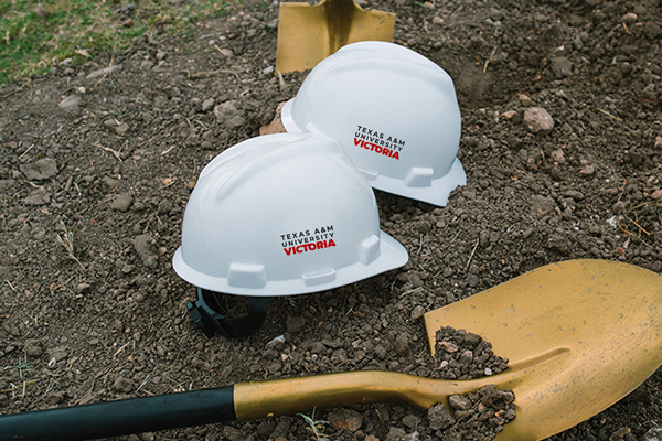 White hard hats with A&M-Victoria logos on them and a gold shovels used at groundbreaking event