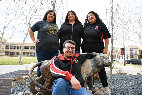 The Velazquez siblings pose with a jaguar statue.